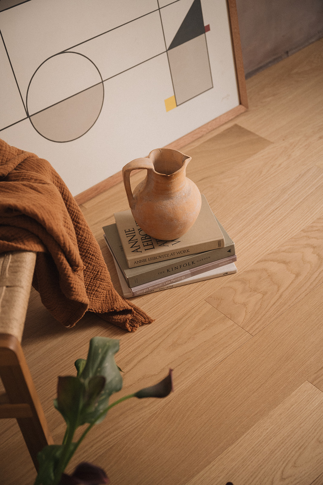 Piso de madera de roble claro con jarrón, libros y manta